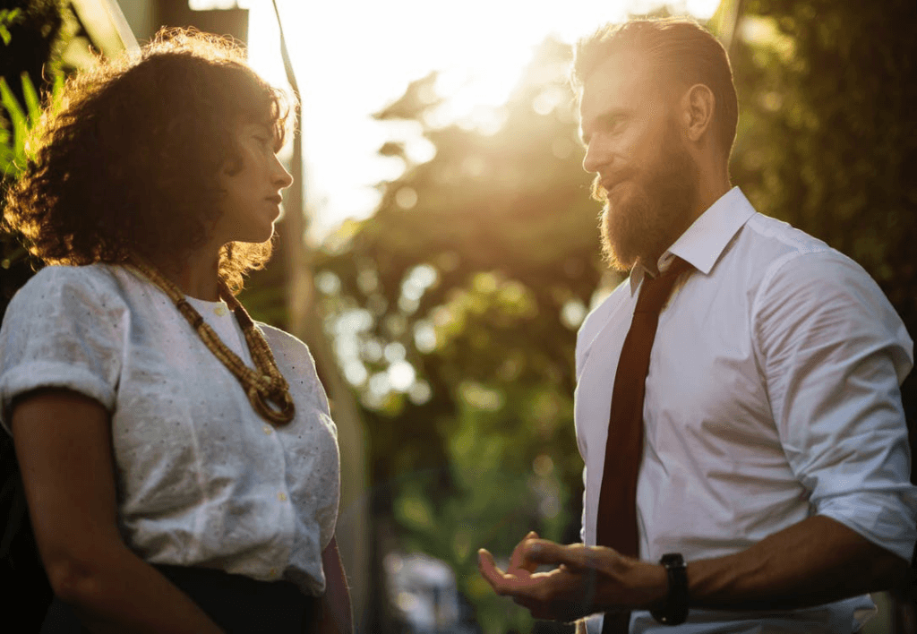 Man en vrouw in een diepgaand gesprek in de buitenlucht tijdens zonsondergang, waarbij de man met zelfvertrouwen en open lichaamstaal communiceert – een voorbeeld van charismatisch worden in sociale interacties